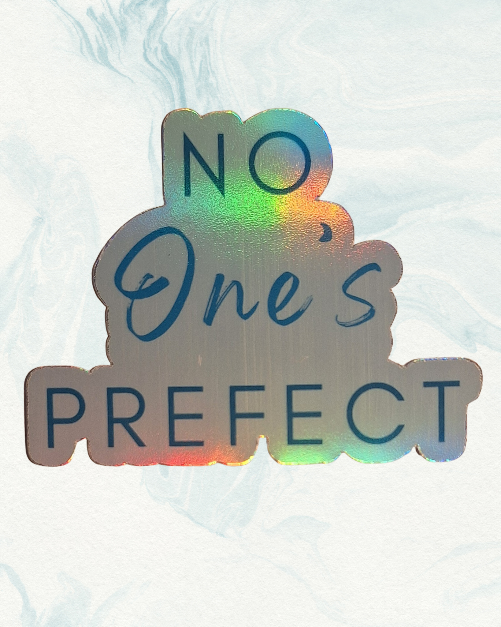 Holographic sticker with 'No One's Prefect' text on a light background